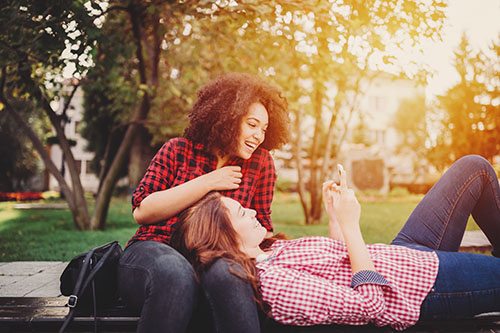 Relaxed girls in the park using smartphone